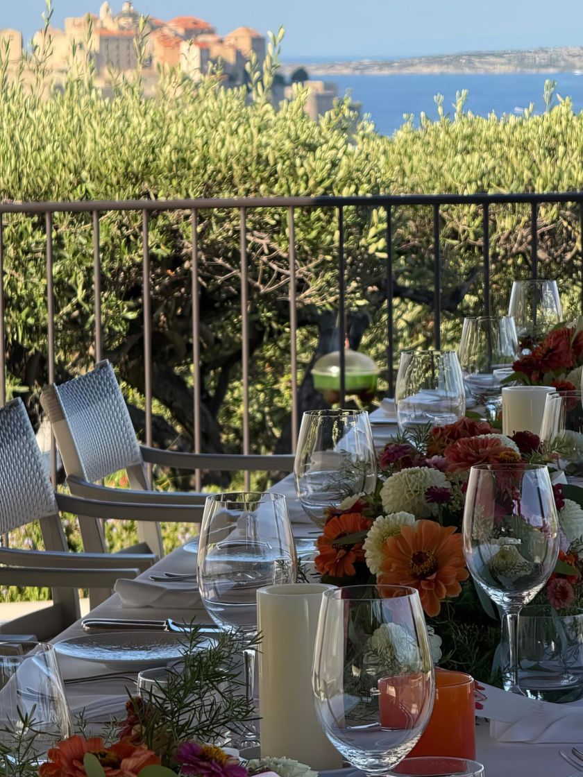 Tavolo apparecchiato sulla terrazza di fronte alla baia di Calvi